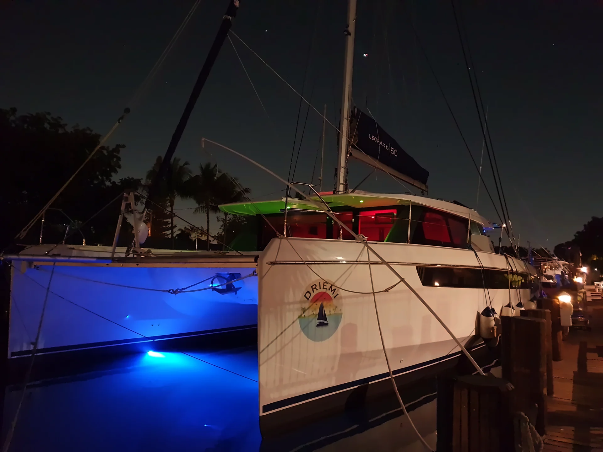 Driemi at night, the DRIEMI logo on the hull and underwater lights glowing blue