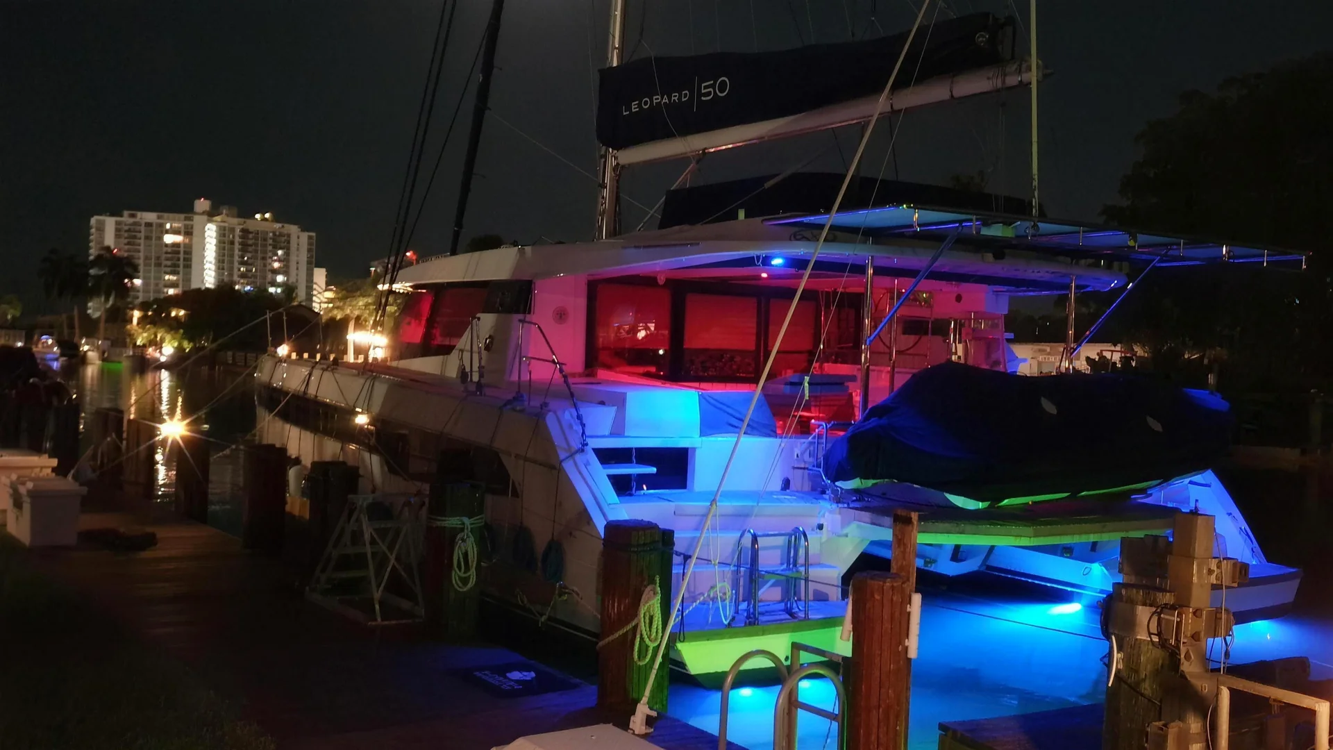 Driemi's stern at night with blue and green lights and the tender on davits